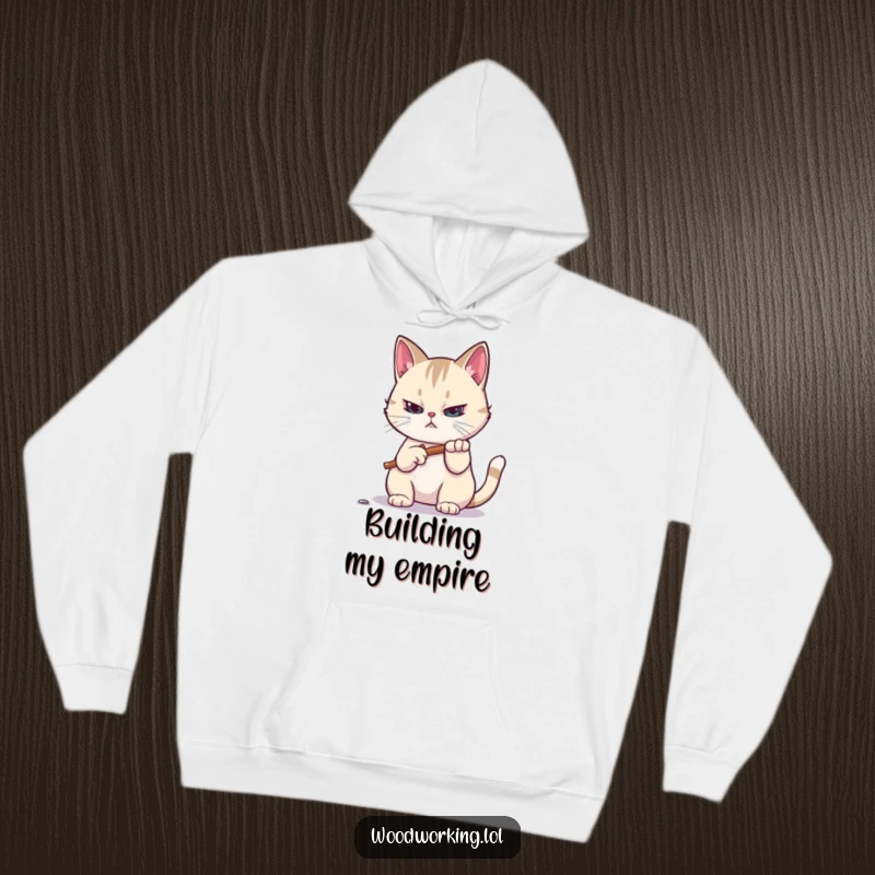 Funny hoodie: A focused cat hammers a tiny nail with determination, offering cozy DIY humor and comfort for workshop enthusiasts as a gift.