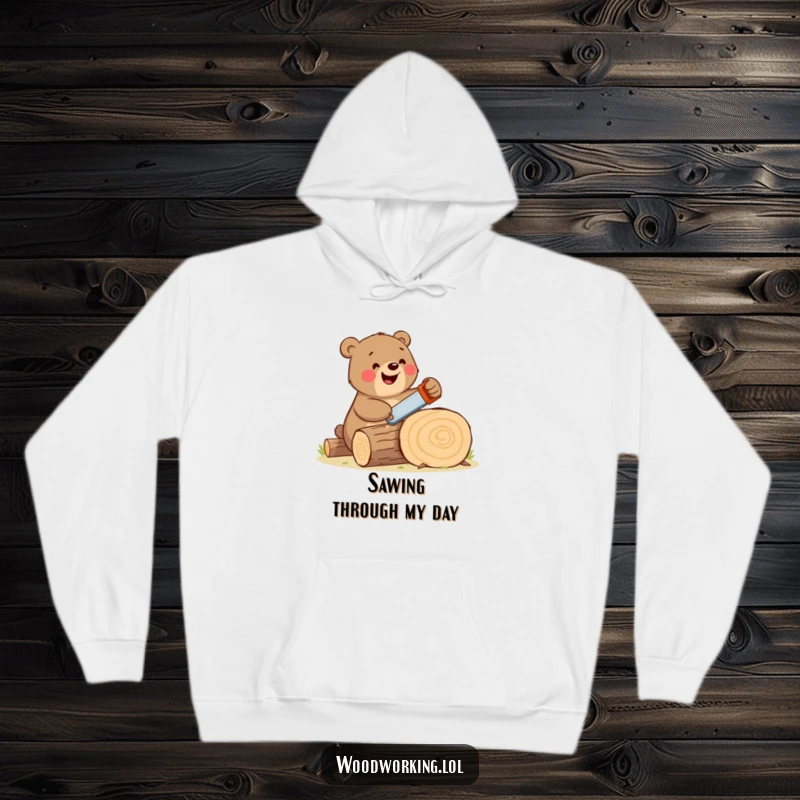 Funny bear hoodie showcasing a happy, large brown bear enthusiastically sawing a log with a comically small handsaw, radiating cheer.